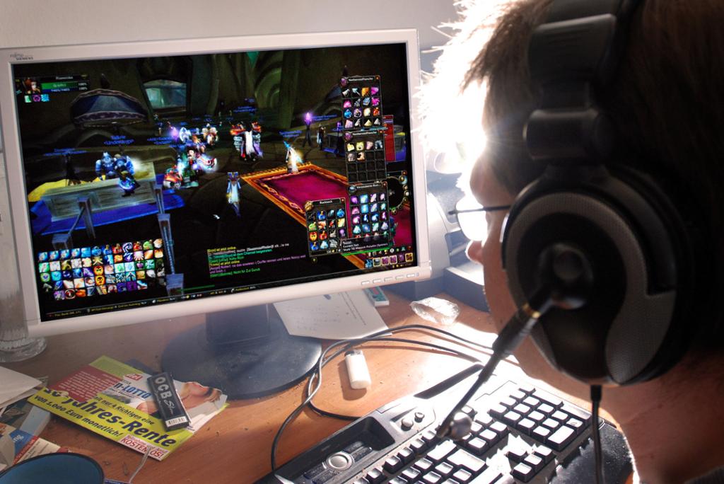 En ung gutt sitter foran en PC-skjerm og spiller. Foto.