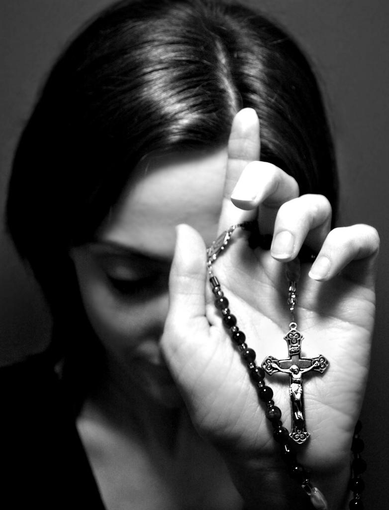 woman holds up her jewlery with a jesus cross on it.photo.