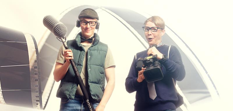 To gutter med briller holder en mikrofon bom og et kamera. Foto.