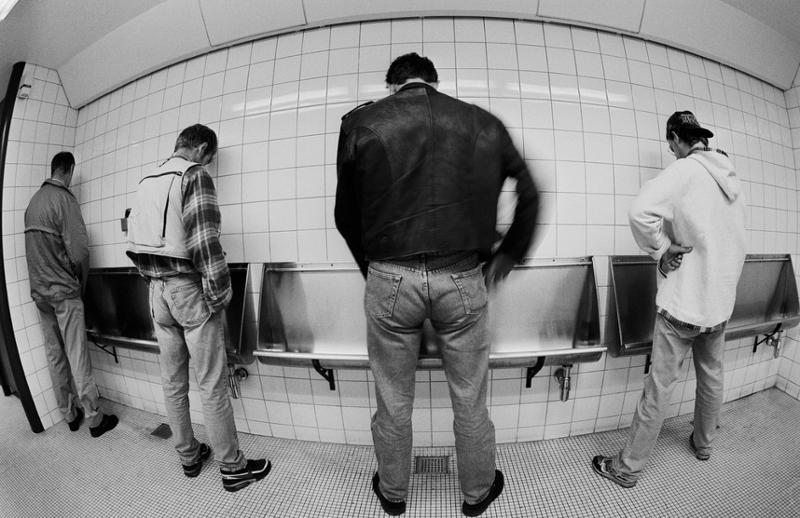 Fire menn som urinerer på offentlig toalett. Foto.