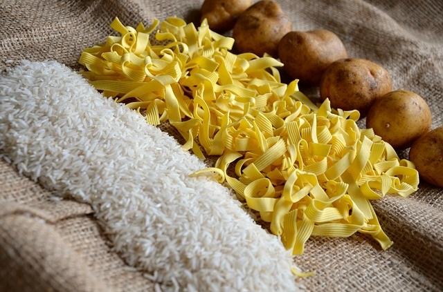 Ris, pasta og poteter ligger i hver sin rekke på en striesekk. Foto.
