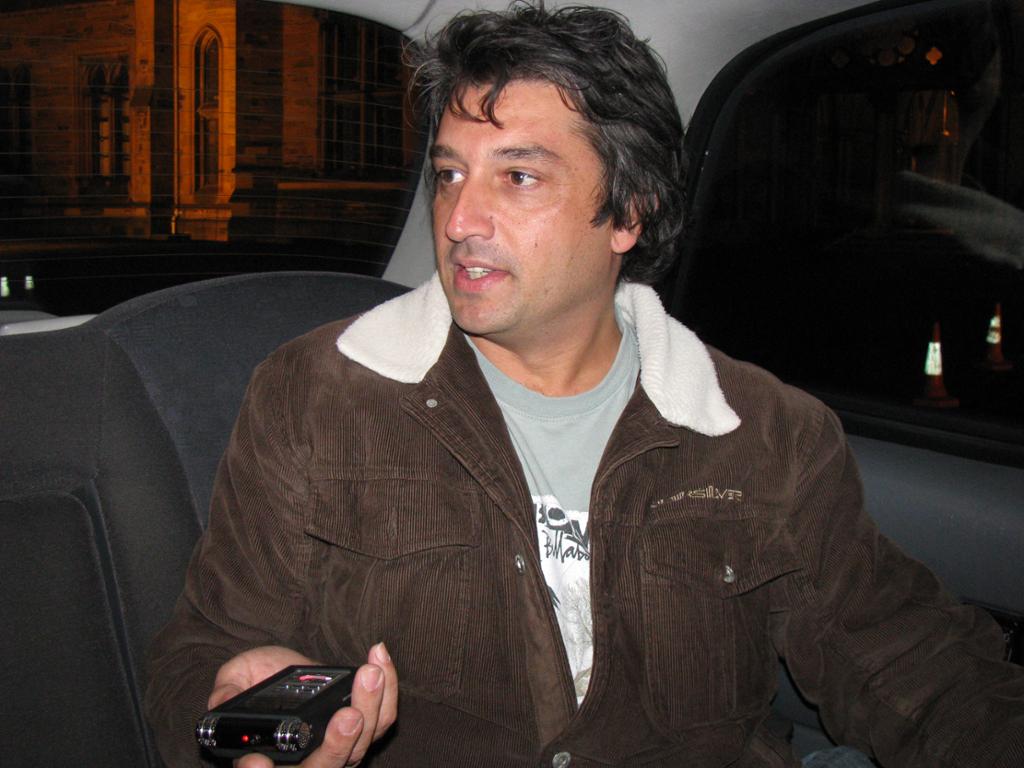 Man sitting in a car, holding a recorder. Photo.