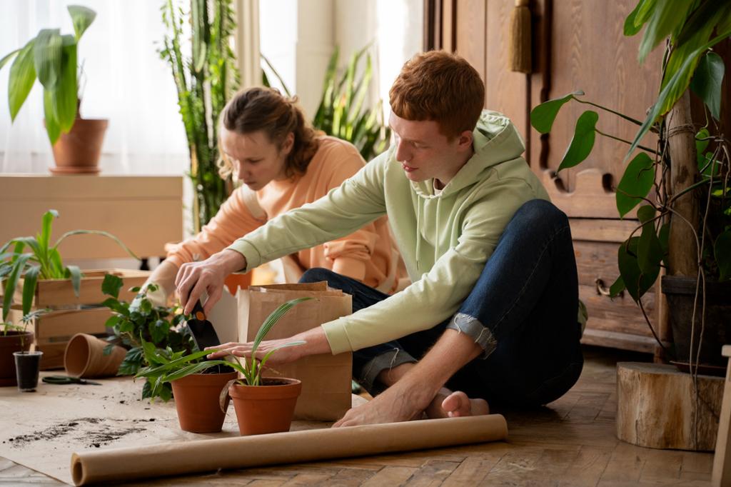 To personer sitter på gulvet og setter planter i potter. Foto.