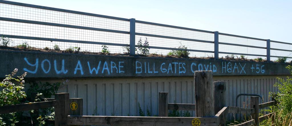 Conspiracy theory graffiti tagged on a building, stating the following: "you aware Bill Gates Covid hoax +5G"