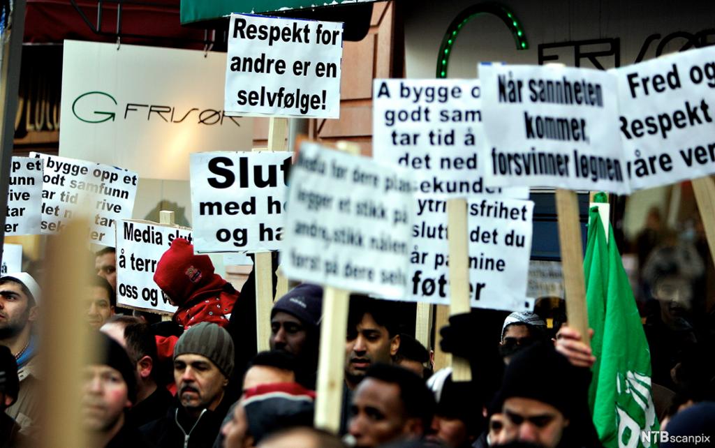 Menn med plakater som ber om respekt for det muslimer holder hellig. Foto.