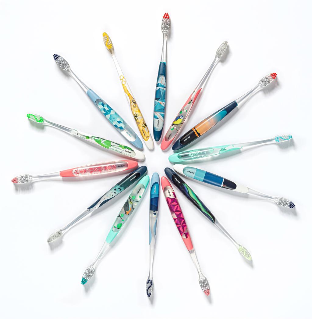 Fjorten tannbørster med ulike fargar i stjerneformasjon. Foto.