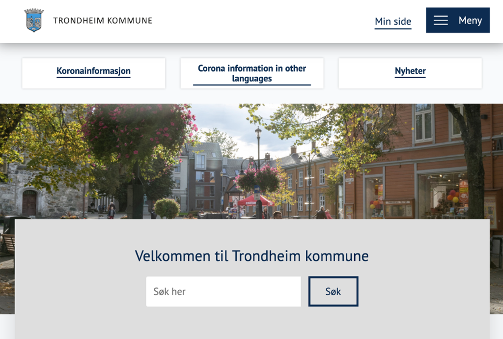 Skjermbilde av Trondheim kommunes nettside. Øverst til høyre er det en menyknapp og en knapp for "Min side". Under disse er det tre bokser med valgene "Koronainformasjon", "Corona information in other languages" og "Nyheter". Bakgrunnen er et bilde fra Trondheim sentrum. Midt på siden står det "Velkommen til Trondheim kommune", og under dette er det et søkefelt. Skjermbilde.