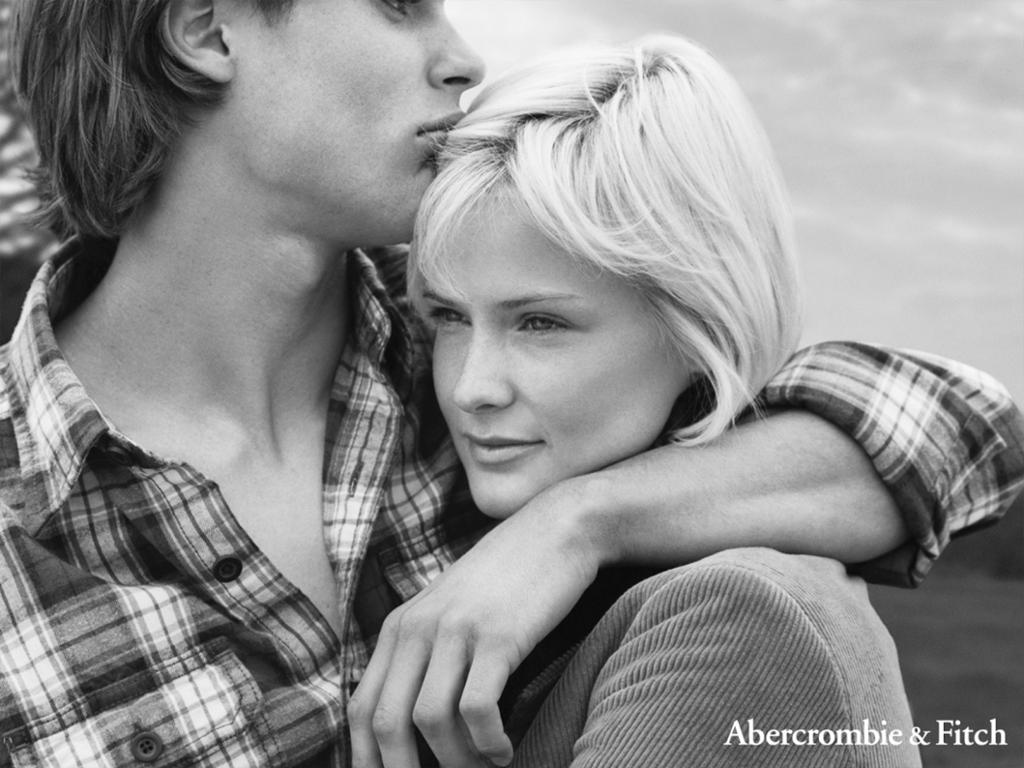 Reklame for klesprodusenten Abercrombie & Fitch med en ung mann som holder kjærlig rundt en ung kvinne. Han er kledd i en rutete skjorte, hun har en jakke i cordfløyel. Sminke og hår er naturlig. Svart-hvitt foto.