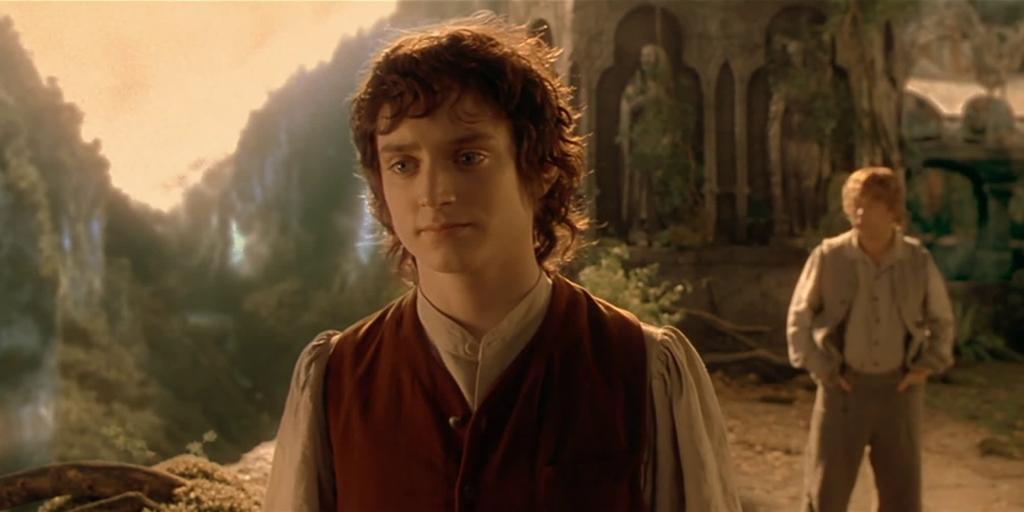 Scene fra filmen "Ringenes herre". Frodo Baggins i forgrunnen, vennen hans Sam i bakgrunnen. Det fins skog og ruiner etter et slott i umiddelbar nærhet. Foto.