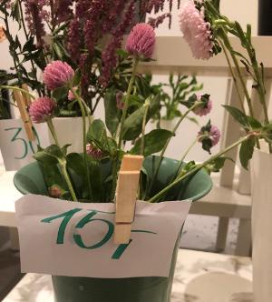 Blomster står i vaser som har papirlapper med priser festet med ei klesklype. Foto