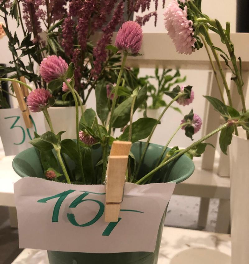 Blomster står i vaser som har papirlapper med priser festet med ei klesklype. Foto