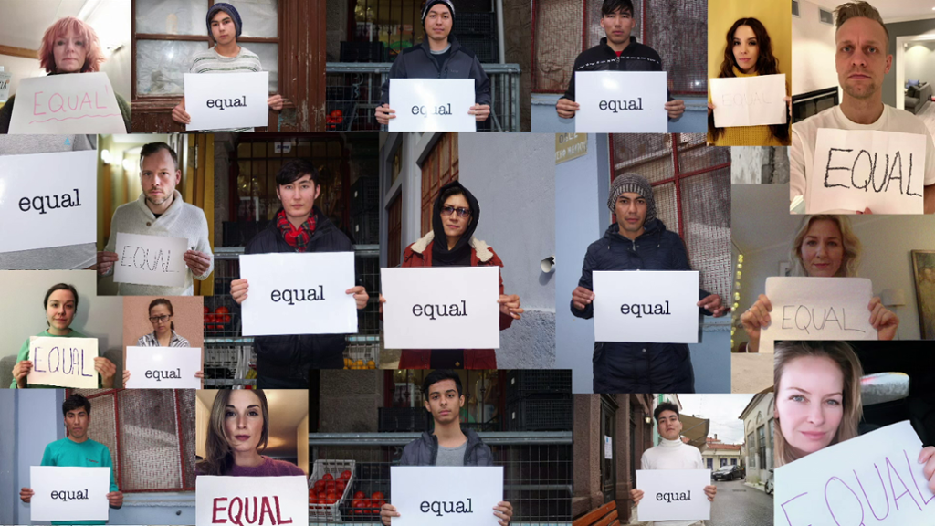 Mange mennesker holder opp plakater det står Equal på. Fra musikkvideoen Menneska.