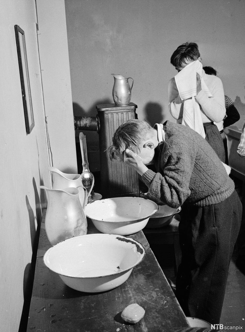 To gutter vasker seg med vaskevannsfat og klut. Foto.