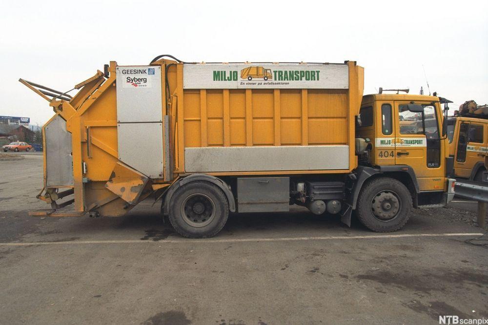 Gul søppelbil med ordet "miljøtransport" i store, grønne bokstaver langs sida. Foto.