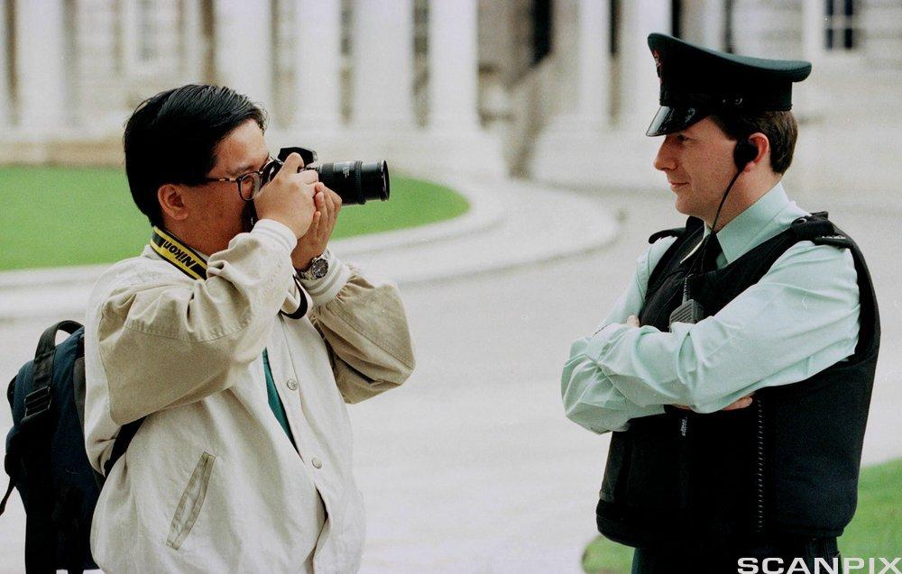 A tourist photographs a Royal Ulster Constabulary officer in Belfast