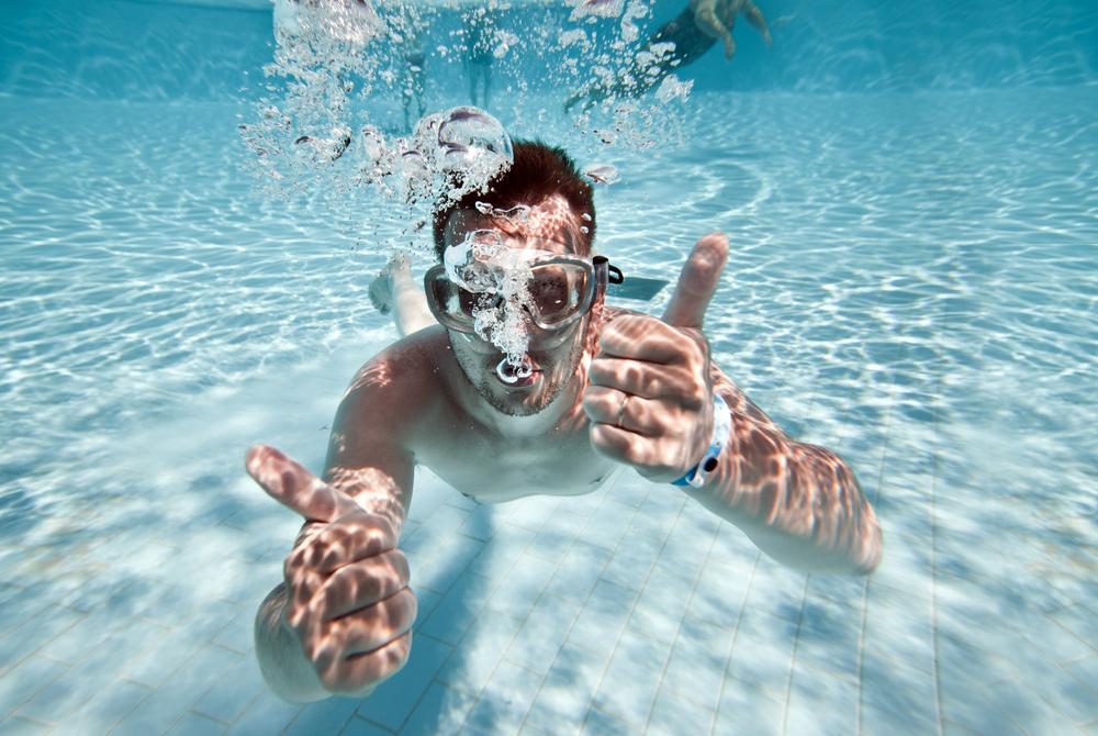 Ung mann svømmer under vann. Foto.
