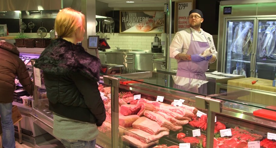 En ferskvarehandler selger ferskt kjøtt til en kunde. Foto.