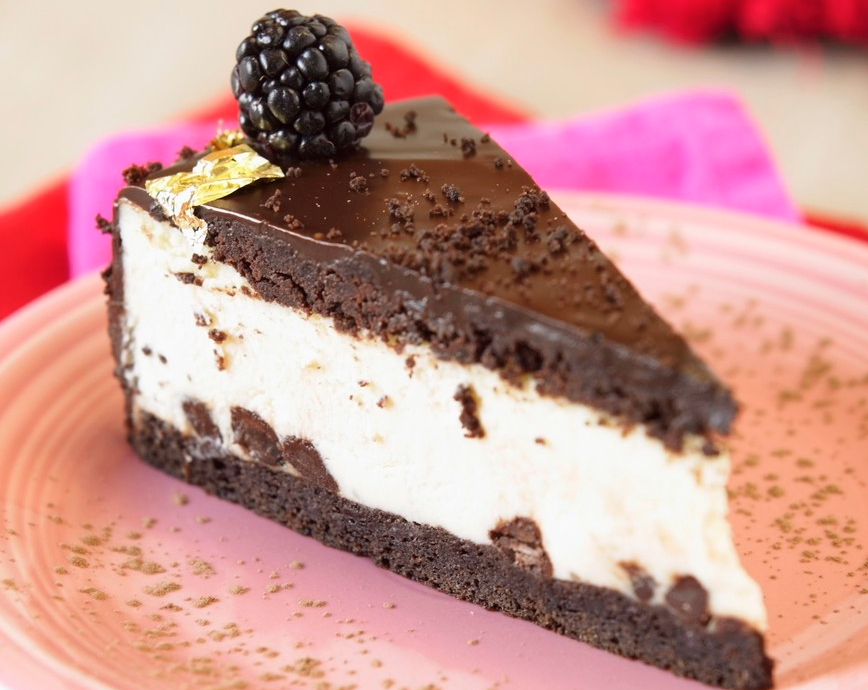 Et stykke glutenfri sjokoladekake med hvitt fyll og bjørnebær til pynt. Foto.