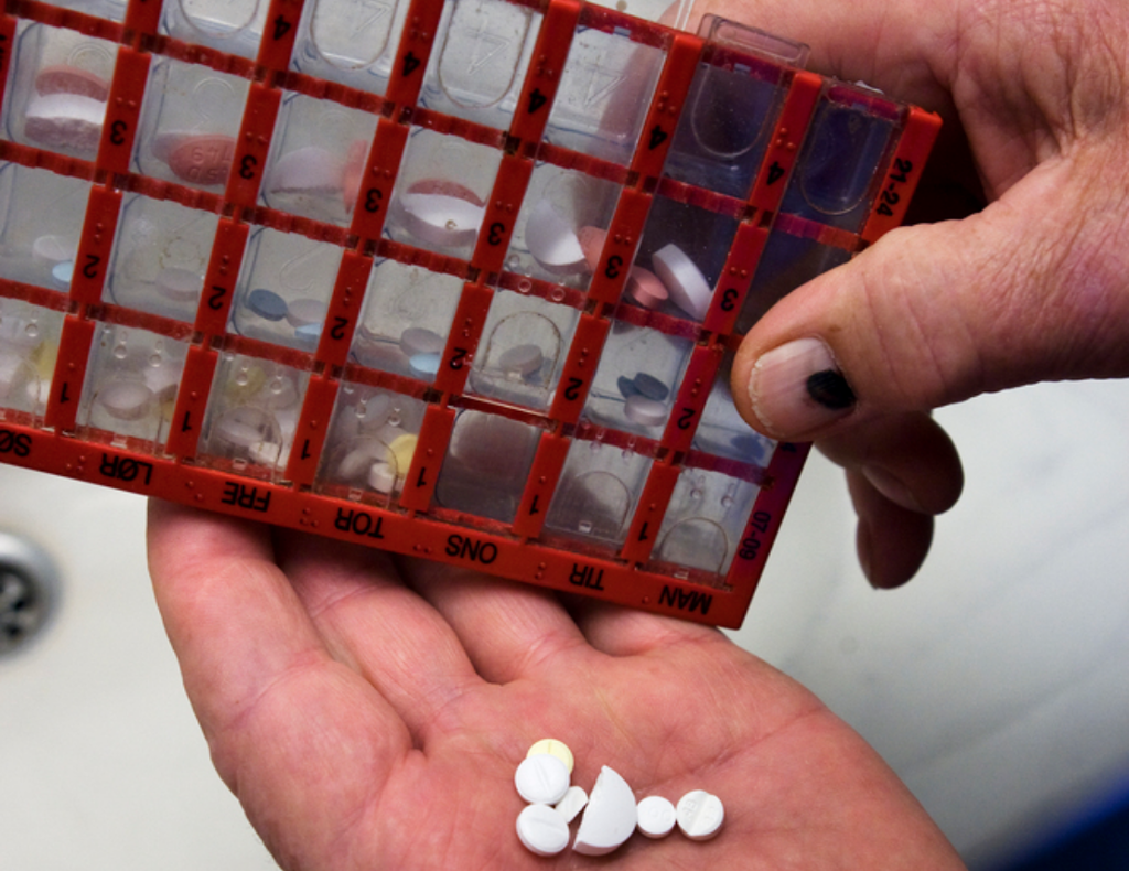 Flere ulike tabletter i ei hånd som holder en dosett. Foto.