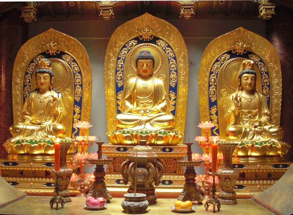 Sittende Buddha i midten, med en figur på høyre side og en på venstre. Skulptur.