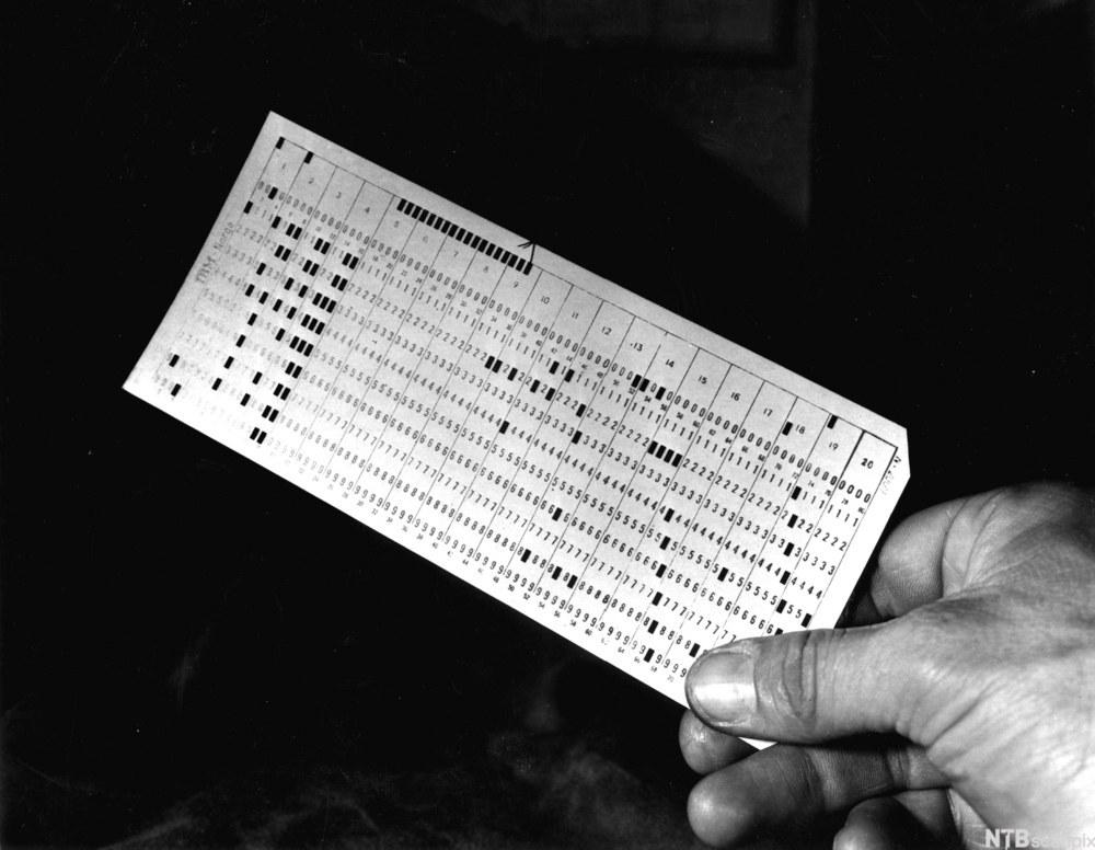 hånd som holder gammeldags hullkort for programmering. Foto