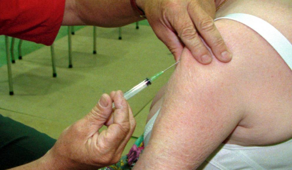 En helsearbeider setter en vaksinenål i overarmen til en dame. Foto.