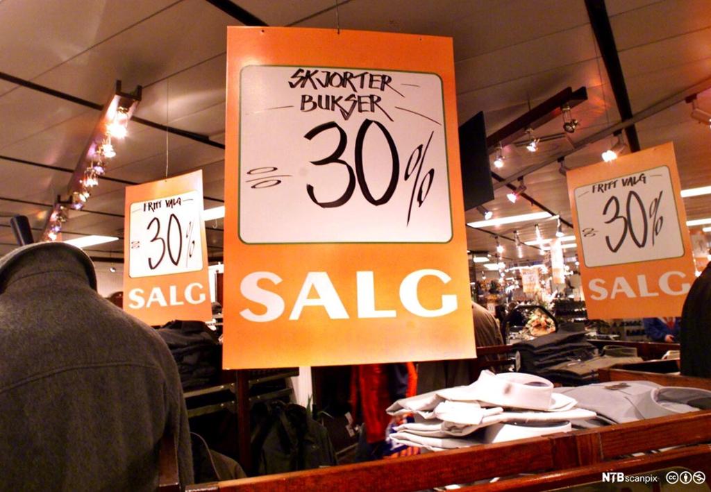  Salgsplakater i klesbutikk viser 30 prosents prisreduksjon på skjorter og bukser. Foto.