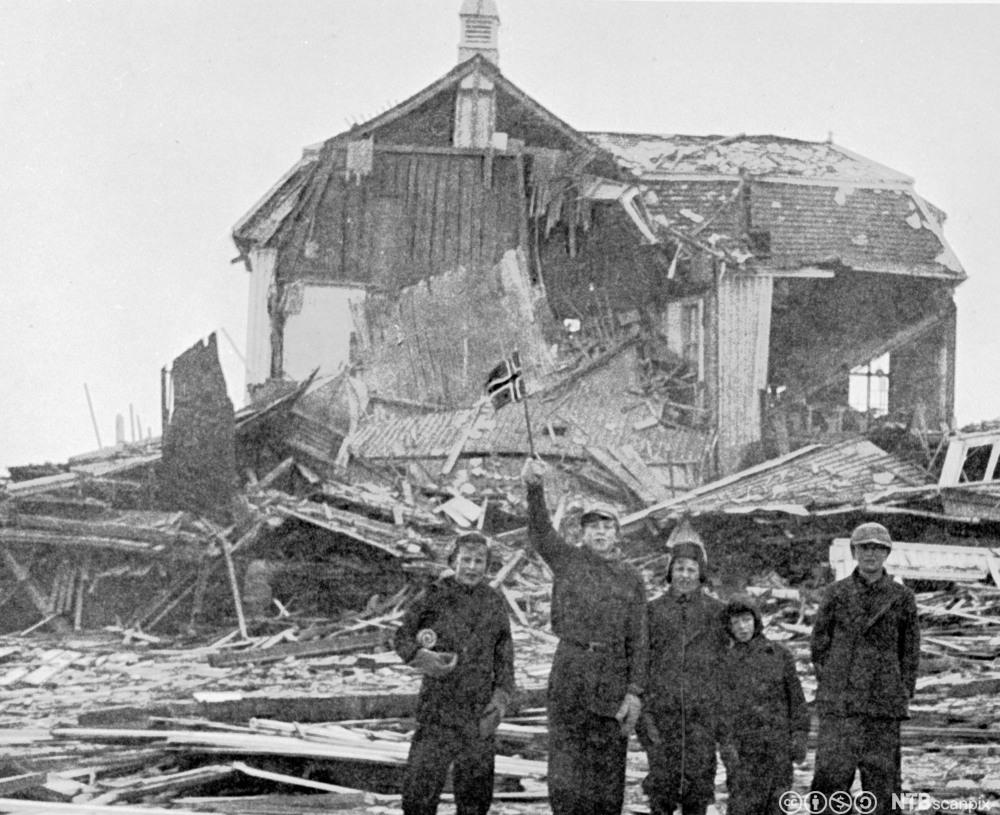 skolebarn med norske flagg foran ruinene av en skole i Vadsø etter nedbrenningen av Finnmark. Januar 1945. Foto.