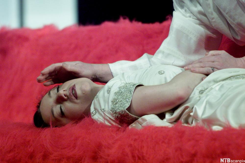 Scene fra Romeo og Julie. Julie har tatt sovemedisin og ligger på ei seng. Romeo tror hun er død. Foto.
