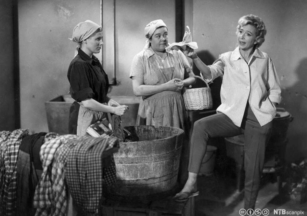 Tre kvinner står og snakker sammen i en vaskekjeller. Foto.