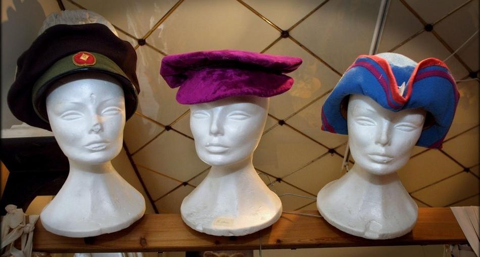 Tre hattar utstilte på dukkehovud. Foto.