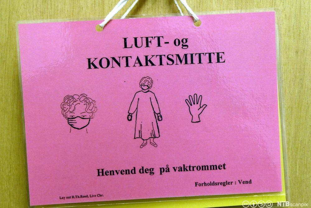Plakat med teskten "luft- og kontaksmitte". Foto.