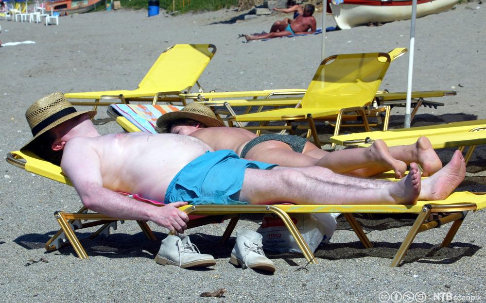 Hvit mann med solhatt på solseng. Foto.