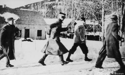 Kong Haakon VII og kronprins Olav (t.v.) under flukten nordover. Kongen og kronprinsen med følge løper her mot skogen for å søke dekning for det tyske flyangrepet på Nybergsund 11. april 1940. Gammelt svart-hvit foto.