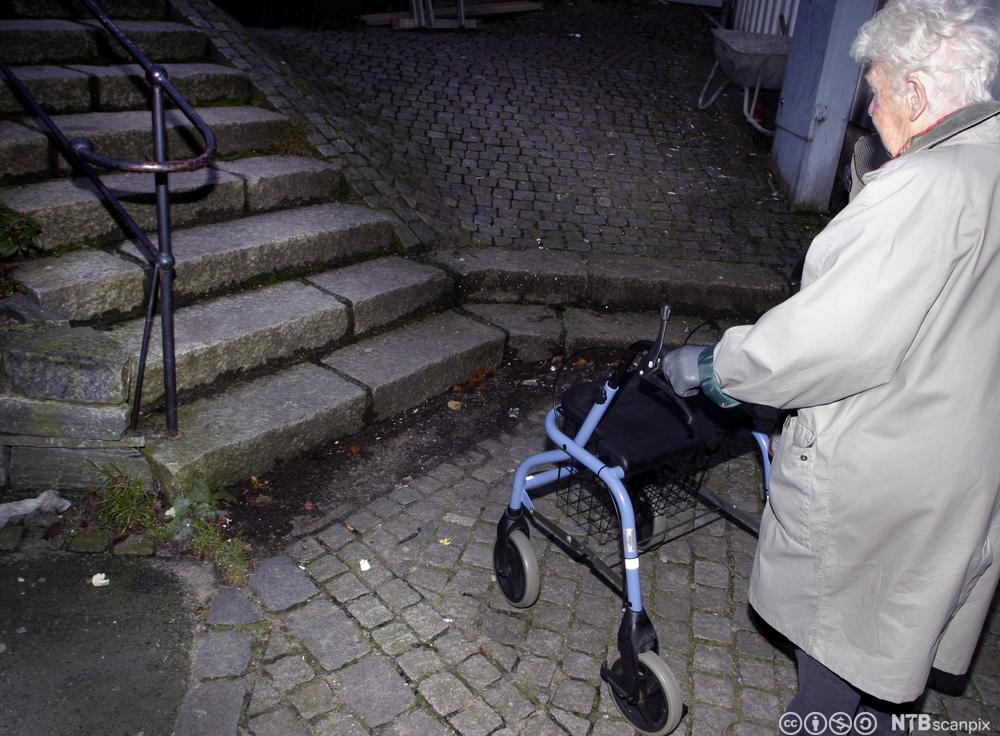 Eldre kvinne stopper ved en en trapp
