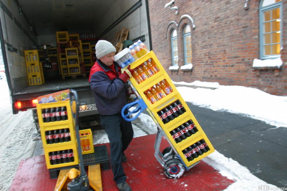 Sjåfør triller bruskasser fra lastebil. foto.