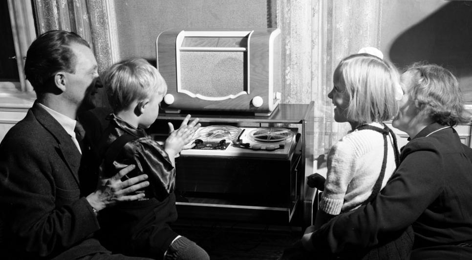 En familie lytter til radio i fellesskap en gang på 1950-tallet. Bilde.