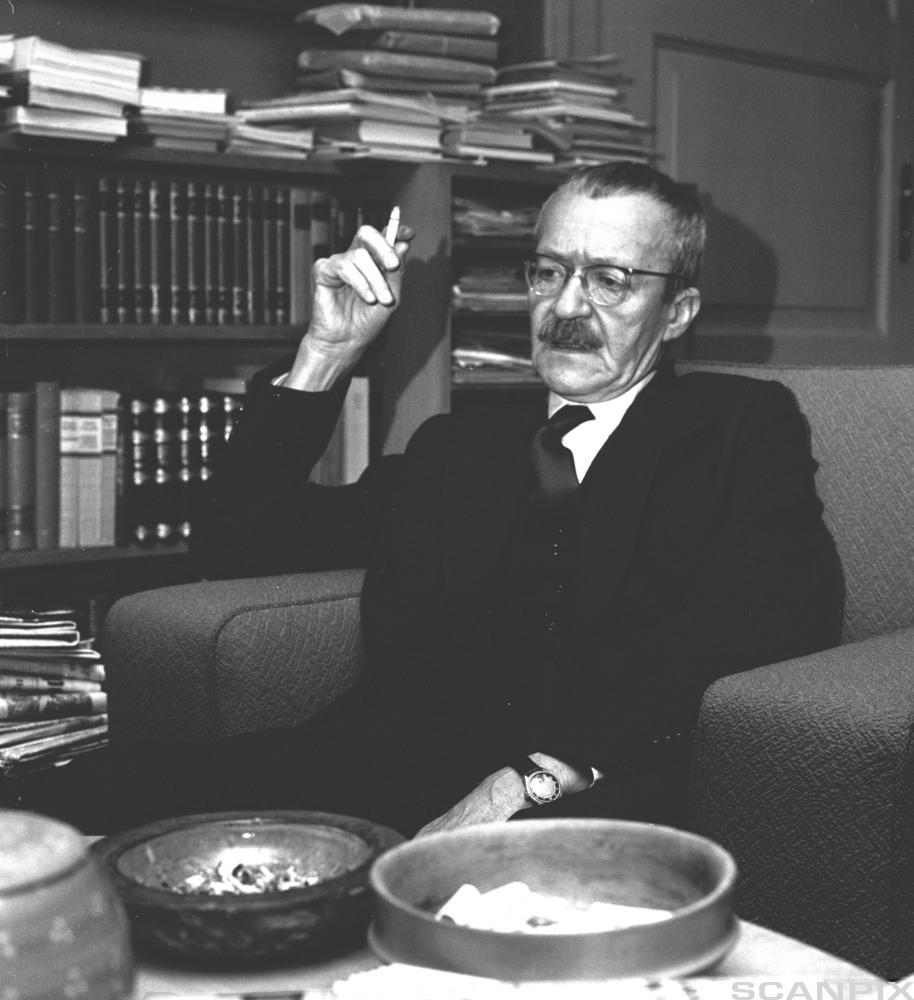 Foto av Arnulf Øverland: Eldre mann med briller og sigarett i sofa. Foto.