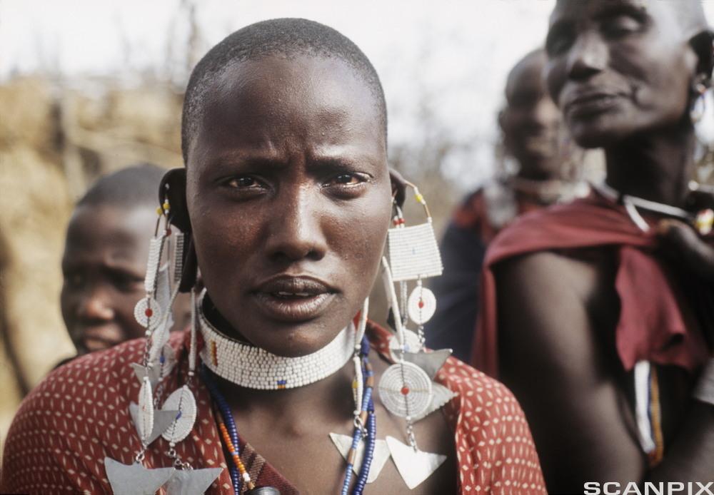 Masaikvinner med store smykker og barbert hode. Foto.