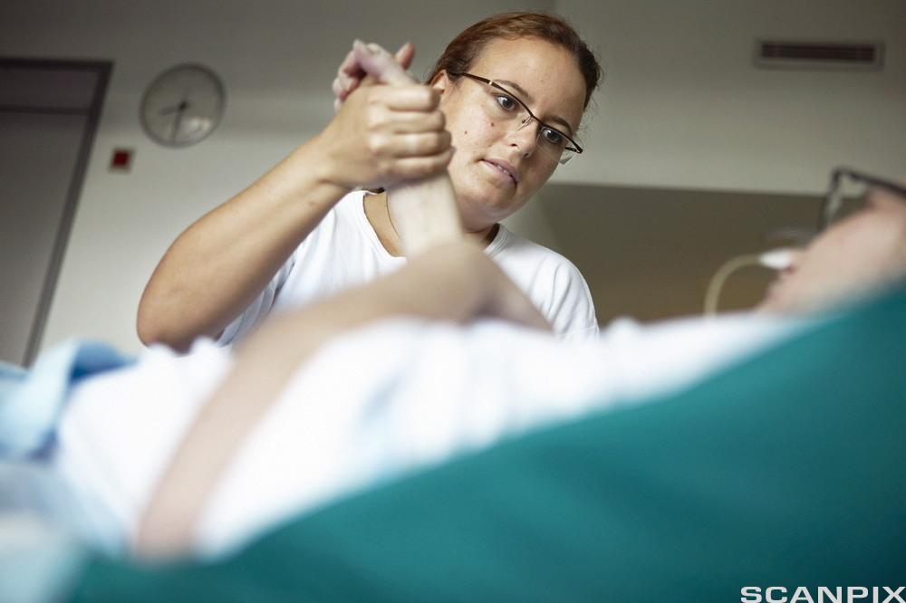 Pleier holder hånden til en pasient. Foto.