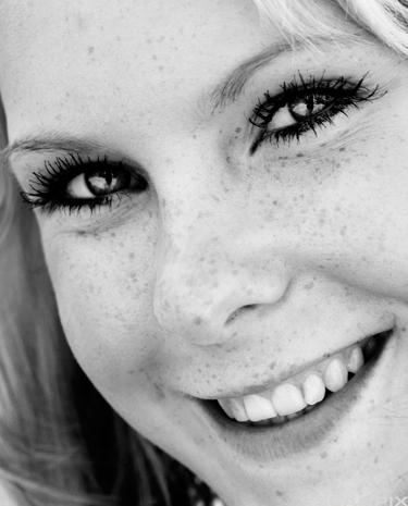 Ung jente med fregner og et stort smil. Foto.