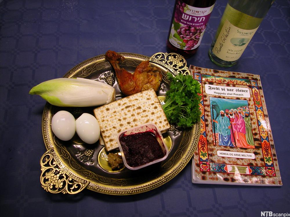 Et tradisjonelt jødisk påskemåltid. På et fat ligger det usyret brød, kylling, egg og salat. Til høyre ligger tekstsamlingen Haggada som brukes under påskemåltidet. Foto.