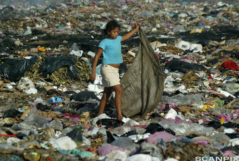 Jente plukker avfall på søppelfylling