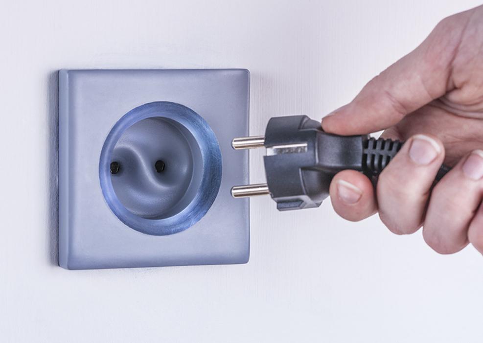 Stikkontakt og hånd som holder støpsel. Foto.