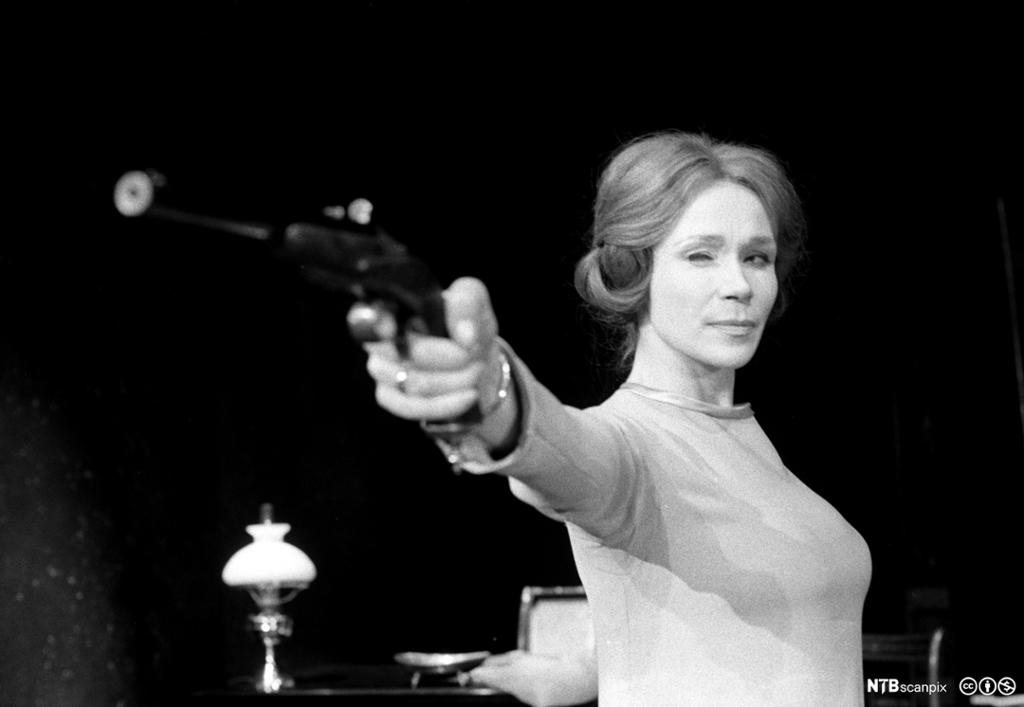 Ei kvinne siktar med ein pistol. Foto.