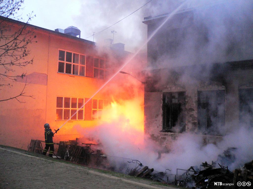 Brannmann slukker brann. Foto.