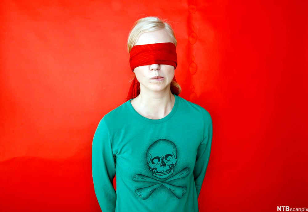 Ung kvinne med bind for øynene. Foto.