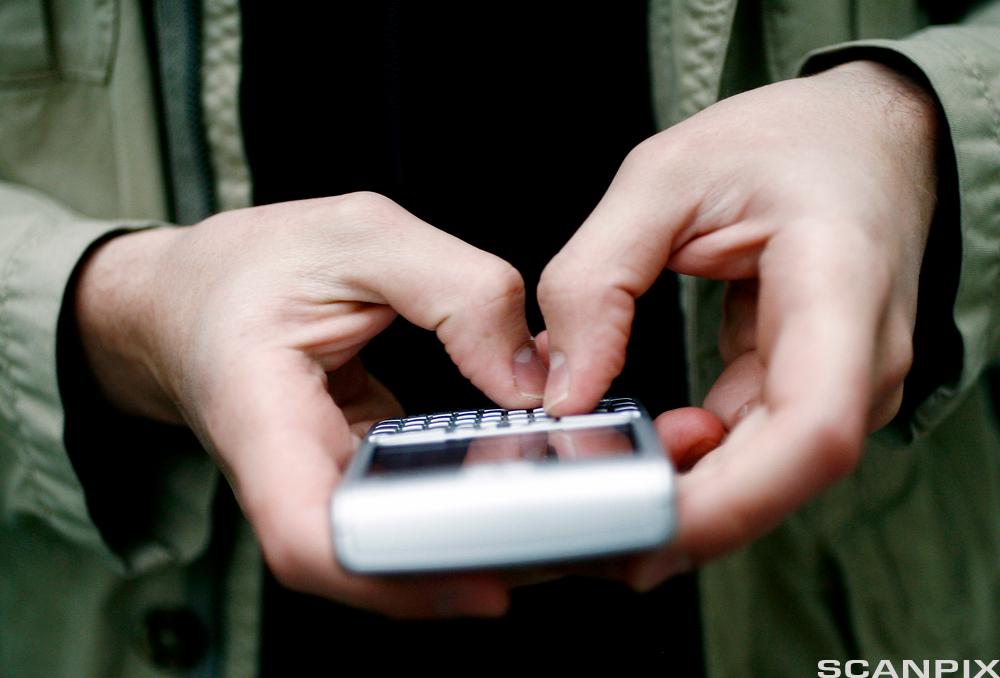 Hender som holder mobiltelefon. Foto.