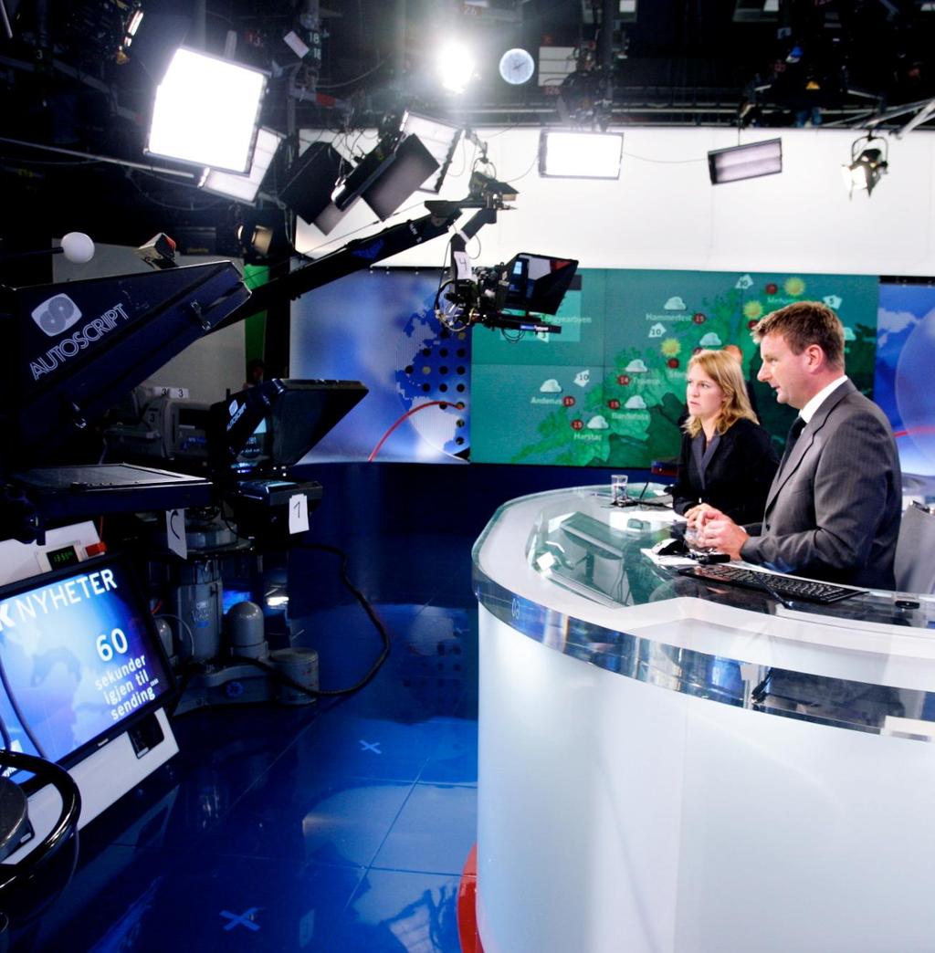 Foto av programlederne Gry Blekastad Almås og Jon Gelius i NRKs nyhetsstudio. I bildet er det flere kameraer og lys og en skjerm med info om direktesending, og i bakgrunnen ser vi værkartet i en annen del av tv-studioet.