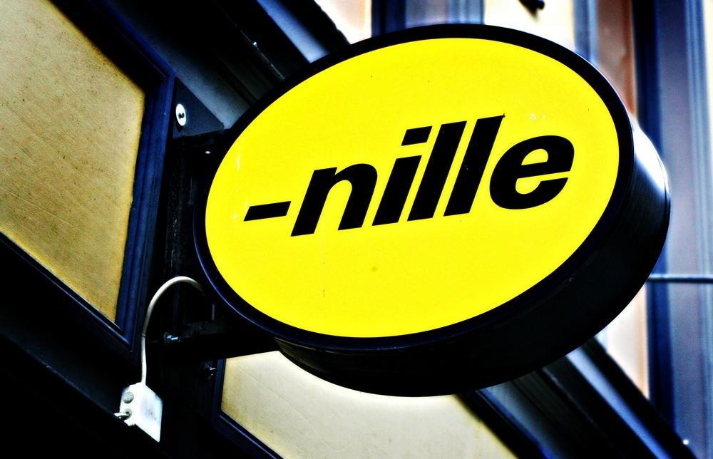 Gult veggskilt med logoen til butikkjeden Nille. Foto.